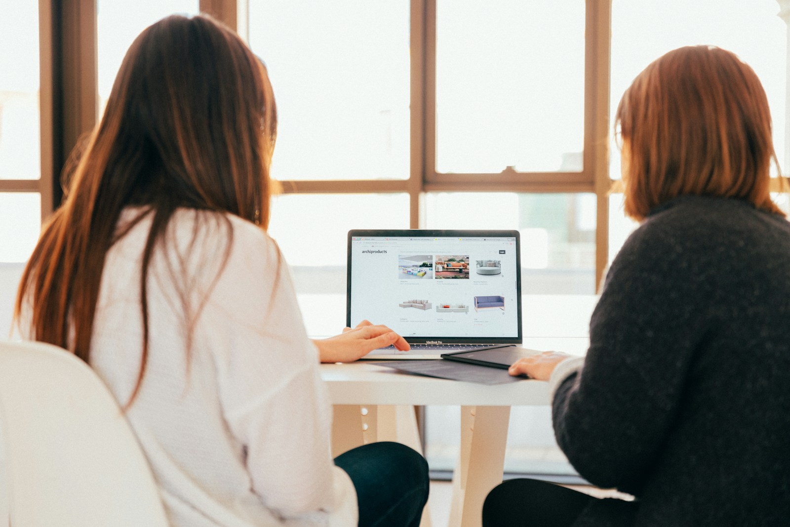 two women talking while looking at WordPress site on a laptop to perform updates